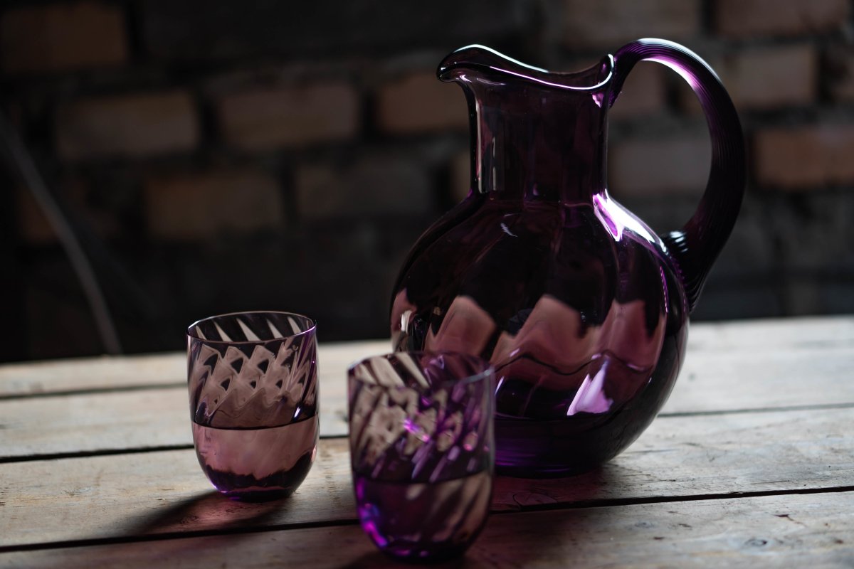 Violet Marika Tumblers on a wooden pallet, with a pitcher from the same collection and a brick base