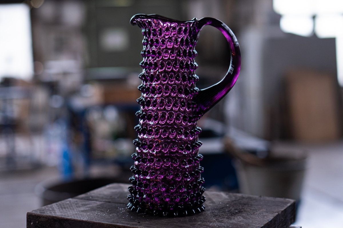 Violet Hobnail Jug Tall on a wooden base with a workshop background