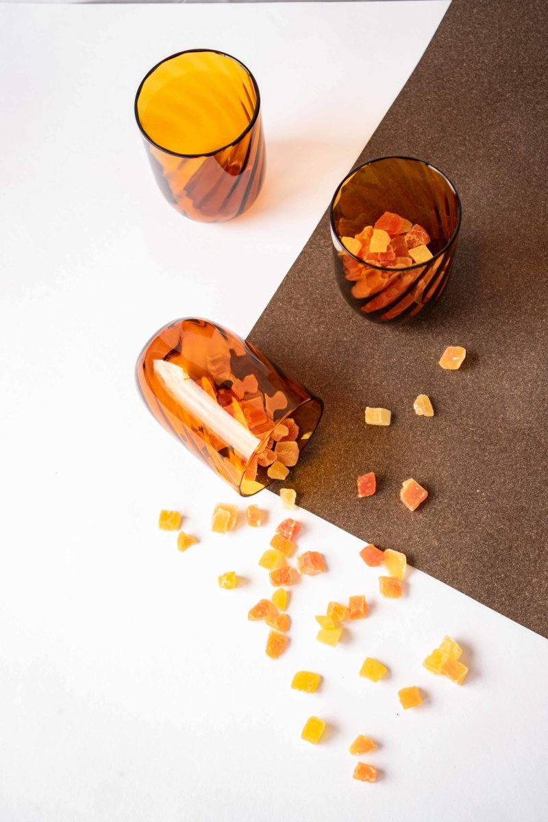 Amber Marika Tumblers on a brown tablecloth with slivers of dried orange fruit